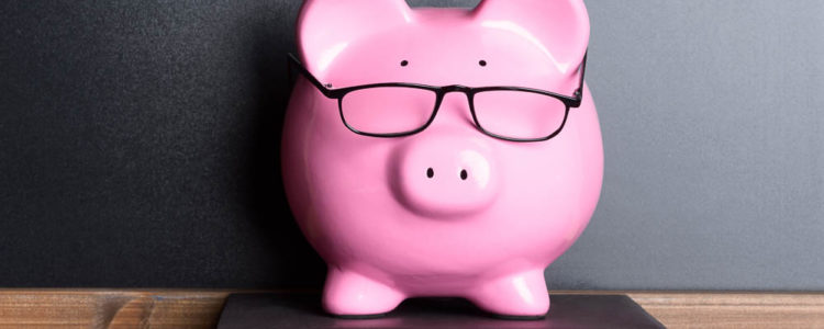 Pink Piggy Bank With Eye Glasses On Book Near Blackboard